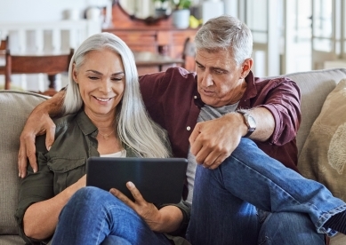 Older couple sitting on couch and looking at ipad